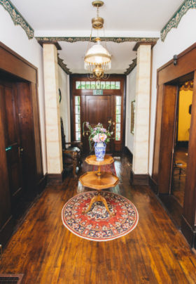 The front hallway of the Old Caledonian, with wooden floors and staircase, is pictured.