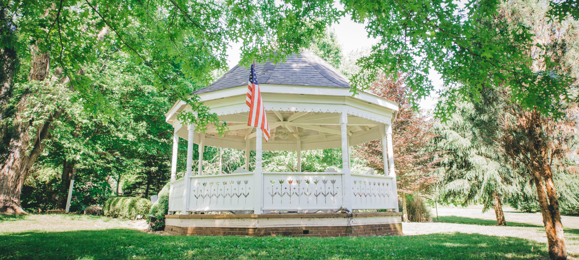 The Old Caledonian's stately gazebo, with green grass and tree boughs, is pictured.