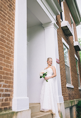 A beautiful bride, bouquet in hand, stands at the portico of the Old Caledonian B&B.